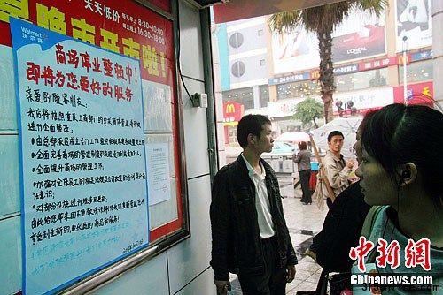 10月11日,重慶市民在萬州沃爾瑪太白路分店超市門口關注停業整頓公告。近日,因涉銷售假冒“綠色豬肉”,沃爾瑪在渝13家門店被當地工商部門責令停業整頓15天。中新社發 趙俊超 攝
